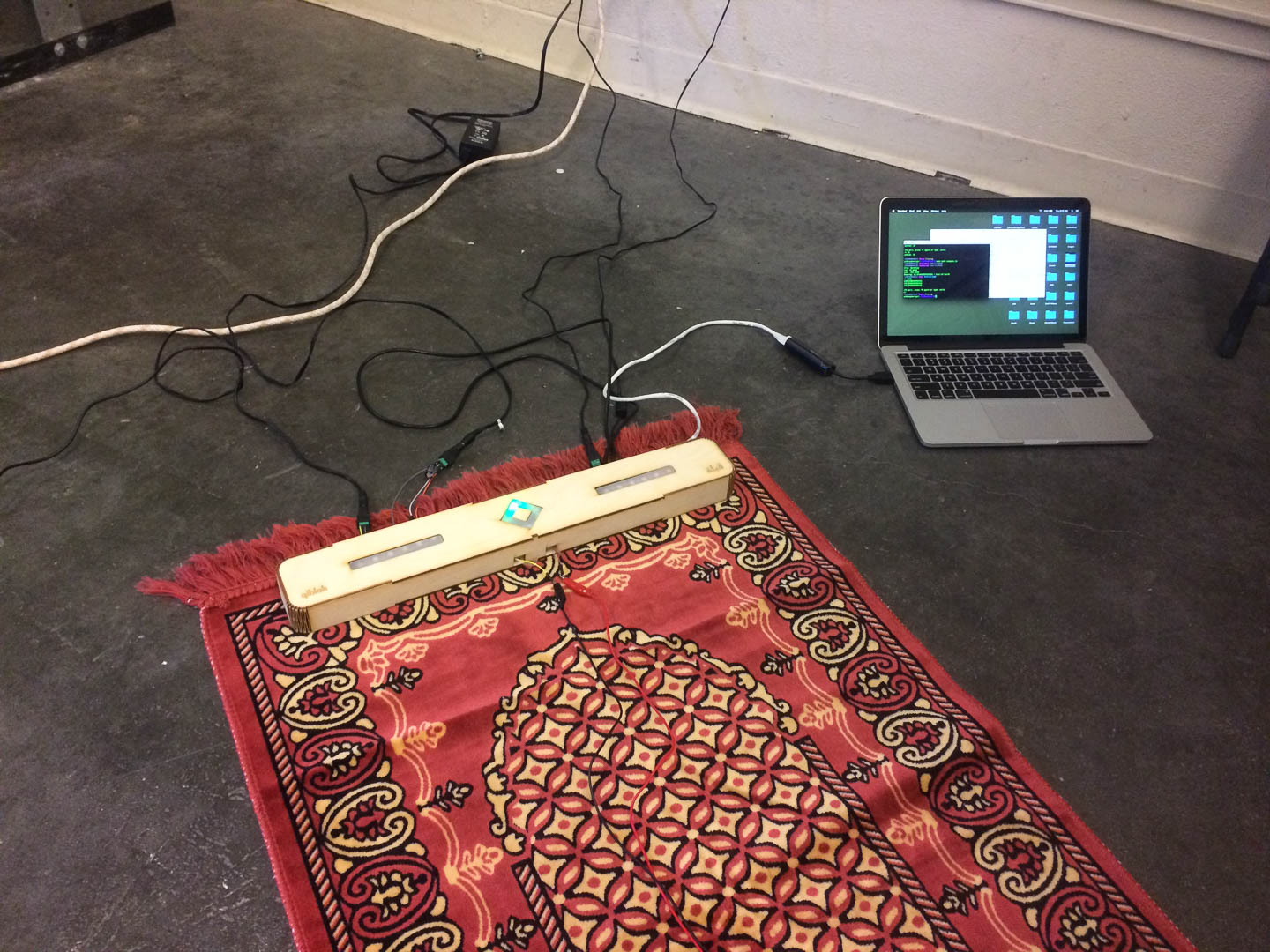Early prototype on a prayer rug, oriented by compass toward the Ka'aba. Laptop running bearing software in the background.